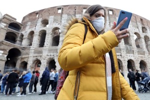 A pedestrian wearing a protective face masks walks past the Colosseum in Rome, Italy, on Tuesday, Feb. 25, 2020. Italy ...