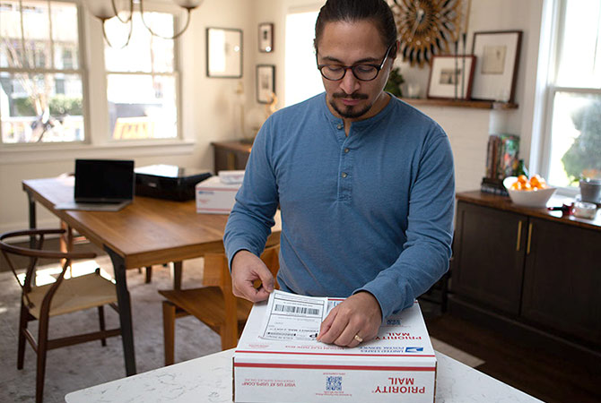 A person placing a Click-N-Ship label on a package.