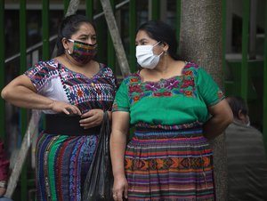 Indigenous women wearing masks to prevent the spread of the new coronavirus stand near the National Palace in Guatemala City, Tuesday, April 14, 2020.