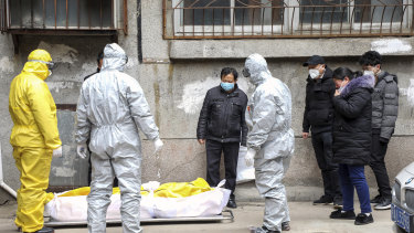Funeral home workers remove the body of a person suspected to have died from the coronavirus outbreak from a residential building in Wuhan in February.
