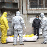 Funeral home workers remove the body of a person suspected to have died from the coronavirus outbreak from a residential building in Wuhan in February.