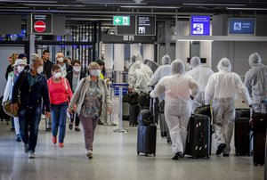 Passengers, left, who just arrived at the airport walk past crew members of South African Airways, right, on their way to the security check at the airport in Frankfurt, Germany, Saturday, April 18, 2020.