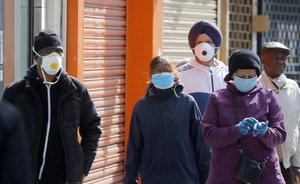 People queue at a post office in front of closed shops during the coronavirus lockdown in London, Tuesday, May 5, 2020.