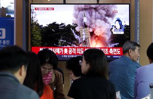 People watch a TV showing a file image of North Korea's missile launch