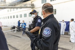 File - Passengers onboard the Celebrity Eclipse cruise ship disembark in San Diego and are transferred by busses  directly to a passenger jet waiting for them at Signature Flight Services at San Diego International Airport. CBP Officers from the San Diego Field Office assisted in the secure transfer of the passengers during the Coronavirus pandemic.