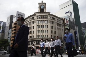 People wearing face masks to help curb the spread of the coronavirus walk at Ginza shopping district in Tokyo Tuesday, May 12, 2020.