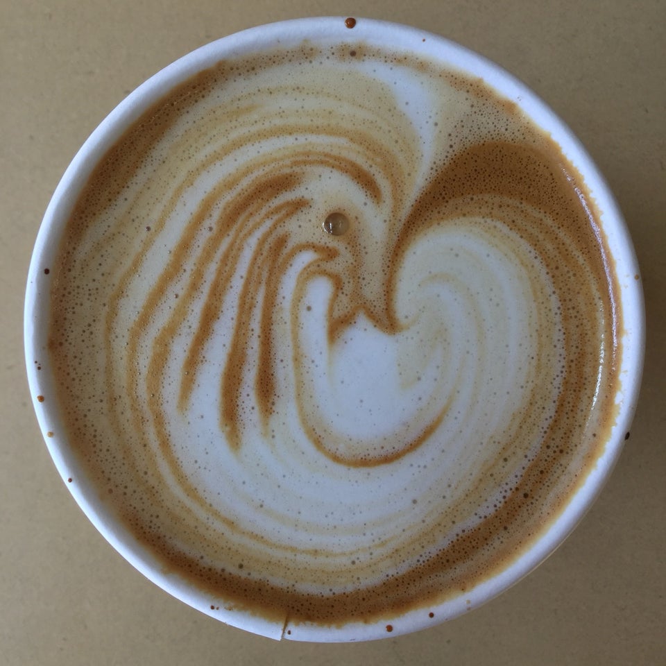 Almond latte with white and brown swirls in a paper cup.