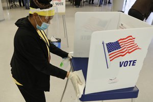 File - Board of elections worker Valerie Tyree cleans an election booth after a person voted in the state's primary election at the Cuyahoga County Board of Elections, Tuesday, April 28, 2020, in Cleveland.