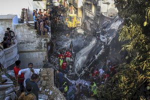 Volunteers look for survivors of a plane that crashed in a residential area of Karachi, Pakistan, May 22, 2020.