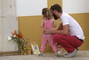 A man and a child look at a picture of missing British girl Madeleine McCann outside the church in the village of Praia da Luz in southern Portugal