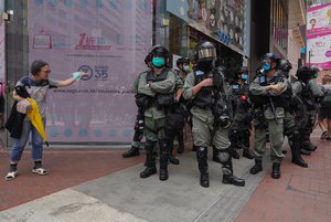 Riot police standing guard as a woman tries to cross the street in the Causeway Bay district of Hong Kong, Wednesday, May 27, 2020.