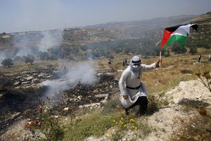 Palestinians run away from tear gas fired by Israeli soldiers during a protest against Israel's plan to annex parts of the West Bank and Trump's mideast initiative ,in the West Bank village of Qusin near Nablus Friday, Jun. 5, 2020.