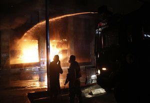 Police use their water cannon to extinguish a shop that was set on fire by protesters during an anti-government protest in Beirut, Lebanon, early Friday, June 12, 2020.