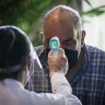 A customer wearing a face mask has his temperature measured at a shopping mall in Rio de Janeiro.