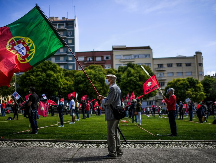 A man wearing a face mask and holding the Portuguese flag takes part in a May Day demonstration in Lisbon.