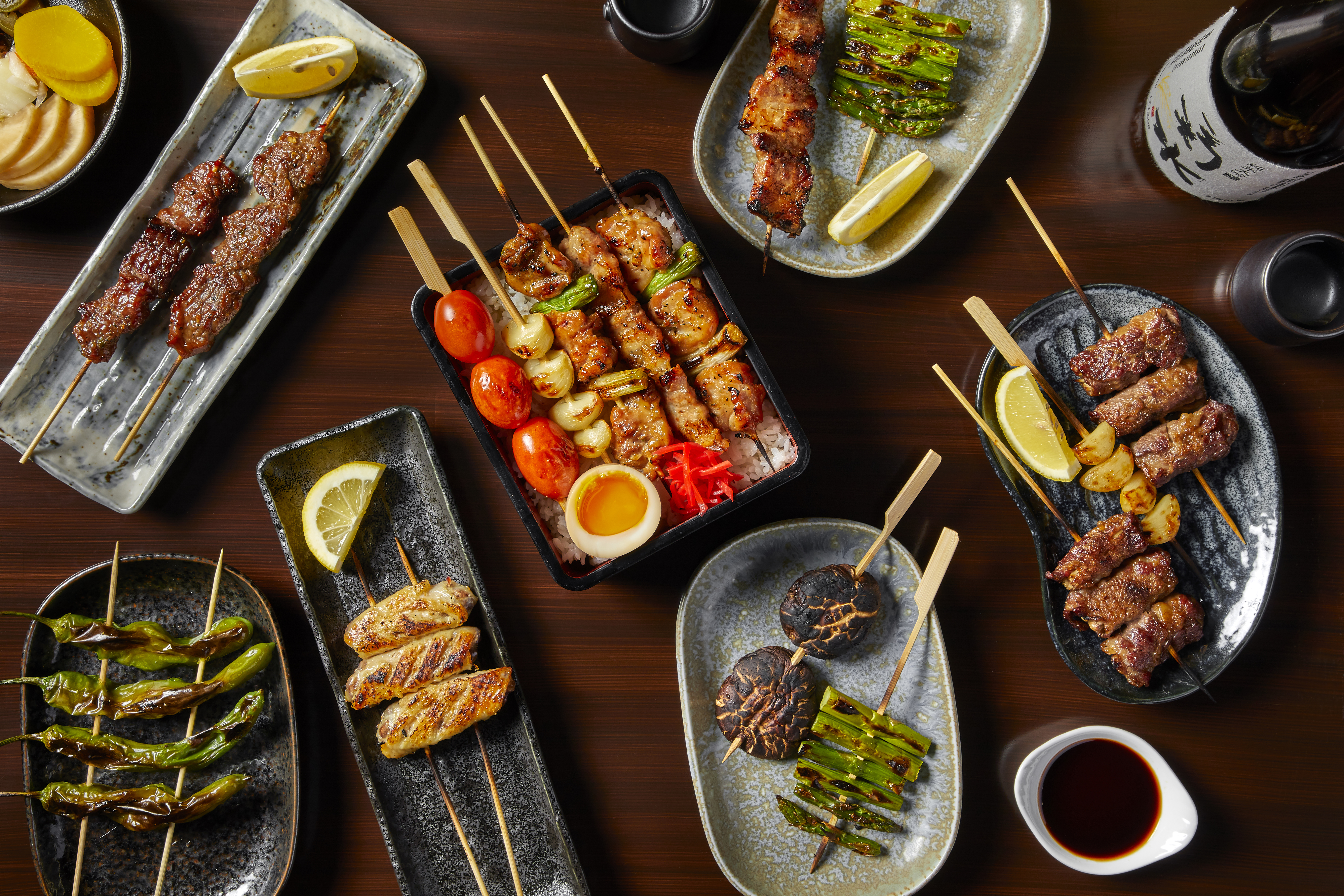 A table fileld with plates of grilled skewers