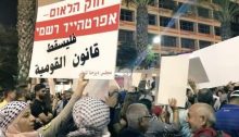 Tens of thousands of protesters demonstrated in Tel Aviv against the "Nation-State Law" in August 2018. The placard held aloft in the foreground reads in Hebrew: "The Nation-State Law – Formal Apartheid”; in Arabic it reads: "Down with the Nation-State Law."