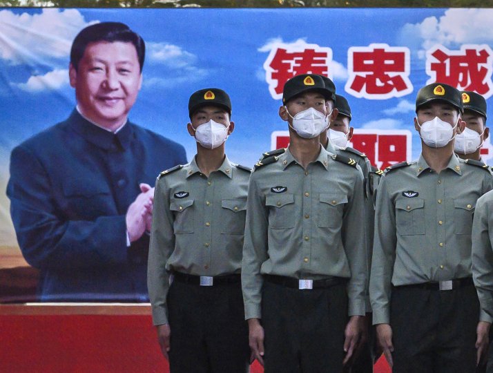 Soldiers of the People's Liberation Army's Honour Guard Battalion wear protective masks as they stand at attention in front of photo of China's president Xi Jinping.