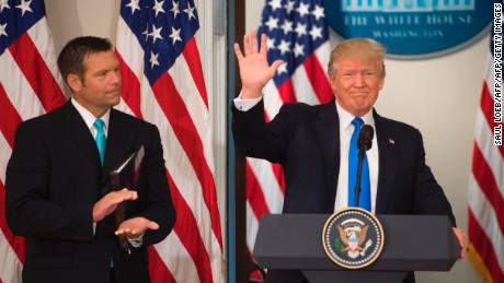 President Donald Trump waves after speaking alongside then-Kansas Secretary of State Kris Kobach in the Eisenhower Executive Office Building next to the White House in July 2017.