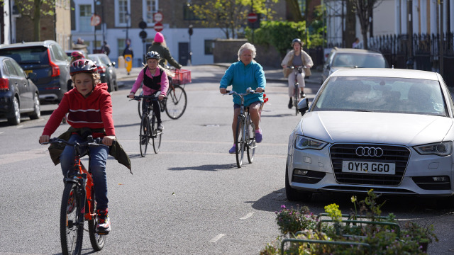 A group of people riding bikes on a quiet city street in the sunshine