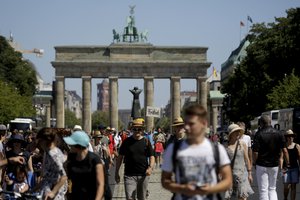 A demonstrator carries a sign reading 'Freedom' in front of the Brandenburg gate as he attends a demonstration with the slogan â€šThe end of the pandemic - freedom day' - against coronavirus restrictions in Berlin, Germany, Saturday, Aug. 1, 2020.