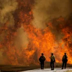 Firefighters watch as flames flare at the Apple Fire in Cherry Valley, California.