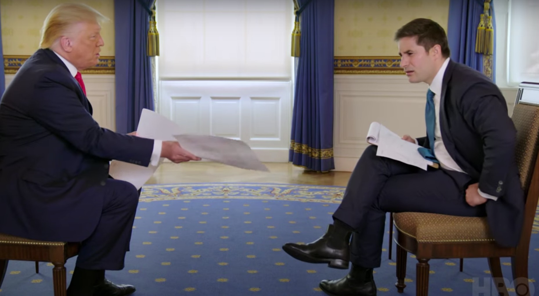 President Trump sitting across from his interviewer and showing him a piece of paper.