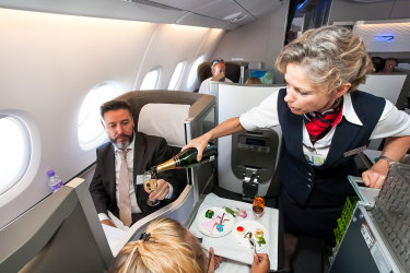 Johannesburg, South Africa - February 06 2014: Female cabin crew pouring a glass of champaign in business class of an Airbus A380 iStock image for Traveller. Re-use permitted. Flight attendant serving drinks in business class on plane