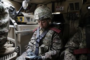 In this Thursday, Jan. 25, 2018 photo, U.S. Army Lt. Aleecia Young reviews briefing notes on a ride into the town of Qaim on Iraq's border with Syria for a meeting with senior Iraqi officers concerned by the ongoing fight against the Islamic State group in Syria