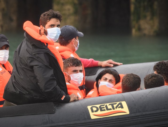 Migrants look towards the waiting media and a small group of protesters after crossing the English Channel from France on August 11, 2020 in Dover.