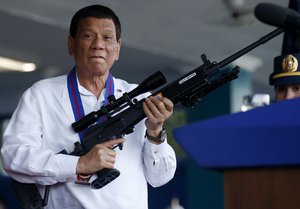 In this Thursday, April 19, 2018, file photo, Philippine President Rodrigo Duterte jokes to photographers as he holds an Israeli-made Galil rifle which was presented to him by outgoing Philippine National Police Chief Director General Ronald "Bato" Dela Rosa, at the turnover-of-command ceremony at Camp Crame in suburban Quezon city northeast of Manila, Philippines. Duterte told the crowd he will not stop his so-called war on drugs until his last day in office.