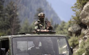 An Indian army soldier keeps guard on top of his vehicle as their convoy moves on the Srinagar- Ladakh highway at Gagangeer, northeast of Srinagar, Indian-controlled Kashmir, Tuesday, Sept. 1, 2020.