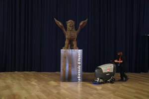 A cleaner sanitizes the floor next to a statue of a winged lion, symbol of Venice and of the Venice Film Festival, inside the Casino Palace, one of the venues of the 77th edition of the Venice Film Festival at the Venice Lido, Italy, Tuesday, Sep. 1, 2020.