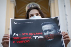 In this Thursday, Aug. 20, 2020 file photo, a protester stands holds a poster reads "poison is the weapon of a woman, a coward and a eunuch!" during a picket in support of Russian opposition leader Alexei Navalny in the center of St. Petersburg, Russia