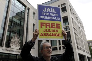 A supporter of Julian Assange demonstrates outside Westminster Magistrates Court in London, Monday July 27, 2020. A case management hearing in the Julian Assange extradition hearing will take place at the court Monday.