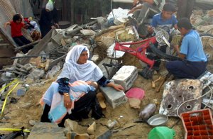 File -  A Palestinian family sit in the ruins of their destroyed home in Gaza, while two boys look over a damaged bicycle, in southern Gaza's Khan Yunis refugee camp.