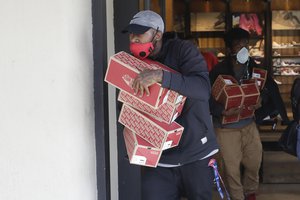 In this May 31, 2020, file photo, items are taken from a Vans store in Santa Monica, Calif., during unrest and protests over the death of George Floyd, a black man who was in police custody in Minneapolis