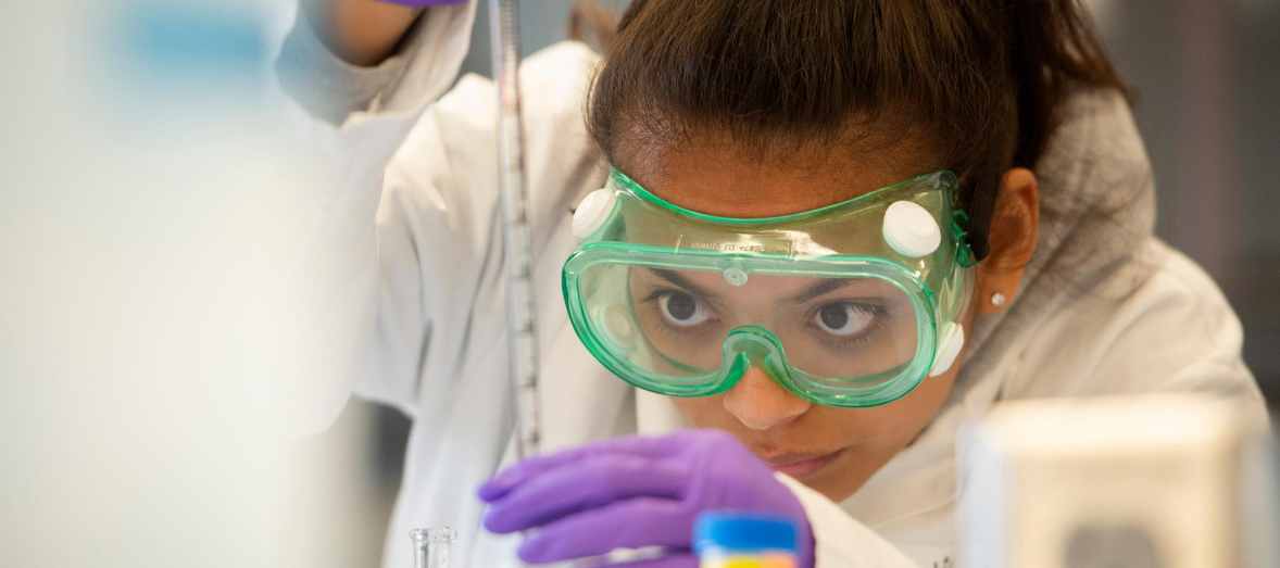 A woman in lab goggles does an experiment