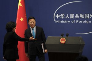 Hua Chunying, left, shows the way to their new spokesman Zhao Lijian on stage during a daily briefing at the Ministry of Foreign Affairs office in Beijing