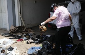 A forensic police investigator holds a skull as she collects human remains from a container sitting in a street outside an office building in Asuncion, Paraguay