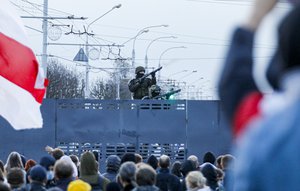 Belarusian riot police stand guard on top of a police barricade blocking a street during an opposition rally to protest the official presidential election results in Minsk, Belarus, Sunday, Oct. 25, 2020.