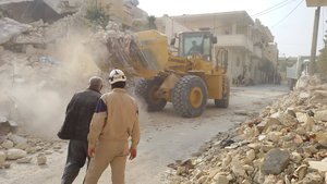 White Helmets, officially known as Syria Civil Defence (SCD), clearing rubble following an attack in Maarat al-Nu'man, Syria, in November 2014, using a USAID-supplied bucket loader.