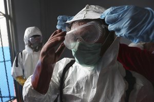 A member of Indonesian Red Cross receives assistance from a colleague to adjust his protective suit as they prepare to disinfect Cipinang Prison compound to prevent the spread of new coronavirus outbreak, in Jakarta, Indonesia, Friday, March 20, 2020.