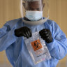 A medical worker seals a coronavirus test in a biohazard bag after collecting a sample.