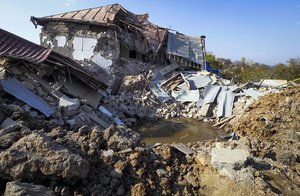 A bomb crater near a house destroyed by shelling by Azerbaijan's forces during a military conflict in Shushi, outside Stepanakert, the separatist region of Nagorno-Karabakh, Thursday, Oct. 29, 2020.