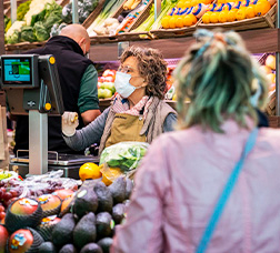 Una dependenta d'una parada d'un mercat amb mascareta