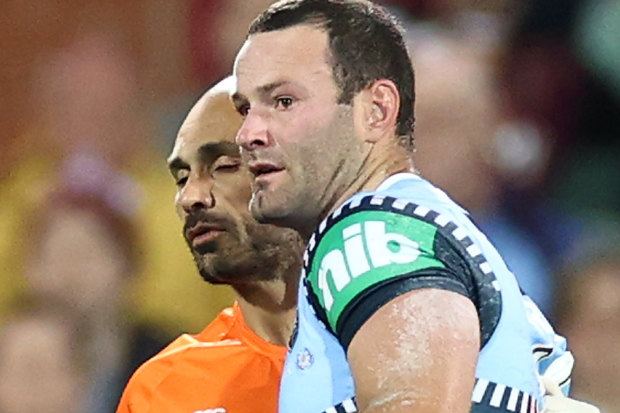 Boyd Cordner is helped from the field by Roosters and Blues trainer Travis Touma.