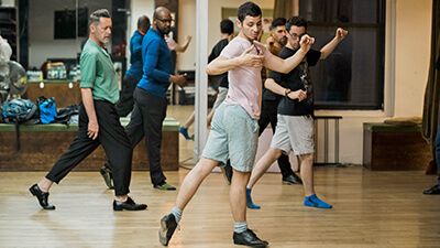 A group of men in a dance studio practicing tap dance