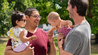 Two fathers having a conversation and holding their infants