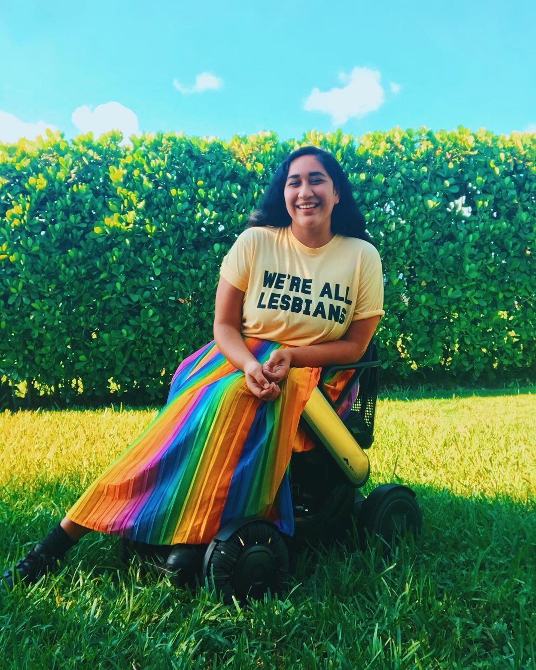 Happy #InternationalLesbianDay 🏳️?🌈❤️⁣
⁣
Chair info bit.ly/AnnieWHILL⁣
⁣
[Image Description: Annie in their backyard sitting in their Whill Model Ci, wearing a rainbow skirt and a yellow shirt that reads, ?We?re all lesbians? from The Prom Musical]...